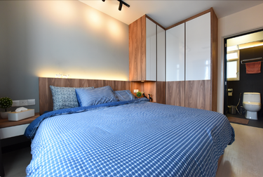 Bedroom with L-shaped wardrobe and bed with blue sheets