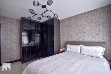 Bedroom with dark L-shaped wardrobe and bed with white sheets