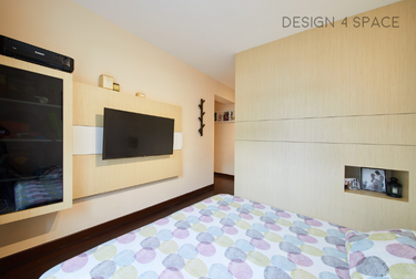 Bedroom with wall-mounted TV and bed with patterned sheets