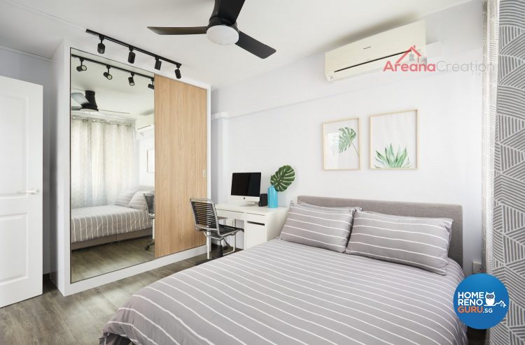 Bed with grey bedsheets and white stripes, ceiling fan, brown wardrobe with full length mirror and study table