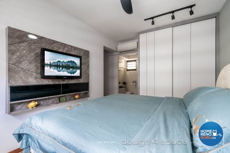 Bedroom with bed with blue bedsheets, white wardrobe and wall-mounted TV