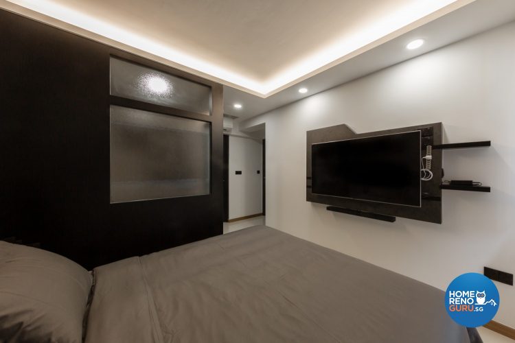 Grey bed, wall-mounted TV and black wall with frosted glass