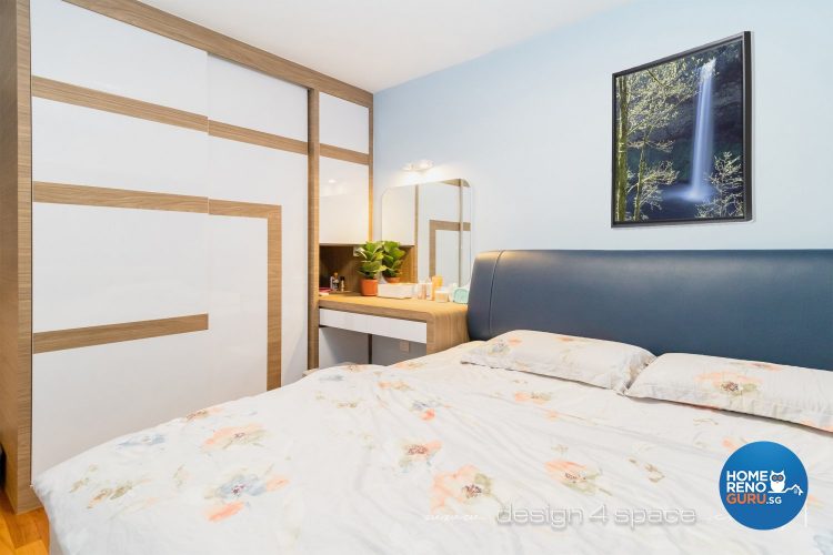 Bed with floral bedsheets, blue headboard and white wardrobe with brown lines