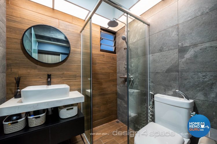 Wooden wall on one side and grey tiled wall on the other side with circular mirror and white toilet bowl