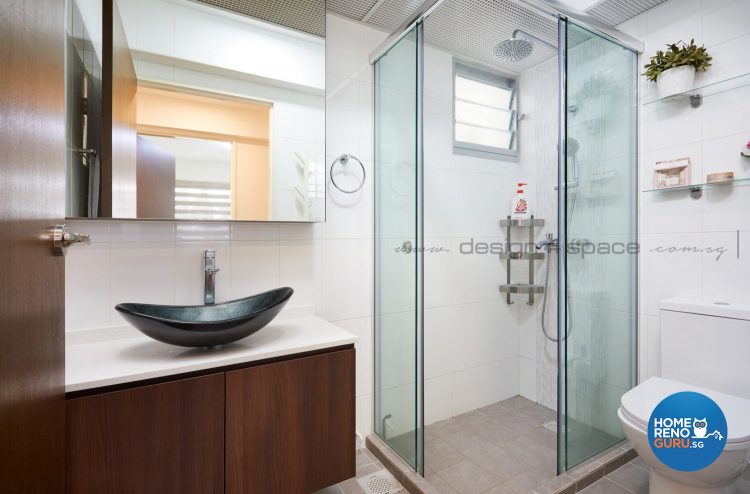 Black sink with rounded edges, brown cabinets and standing shower