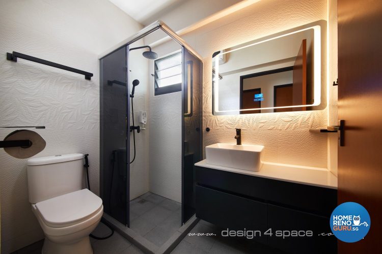 Standing shower with black tinted glass, white toilet bowl and mirror with lights