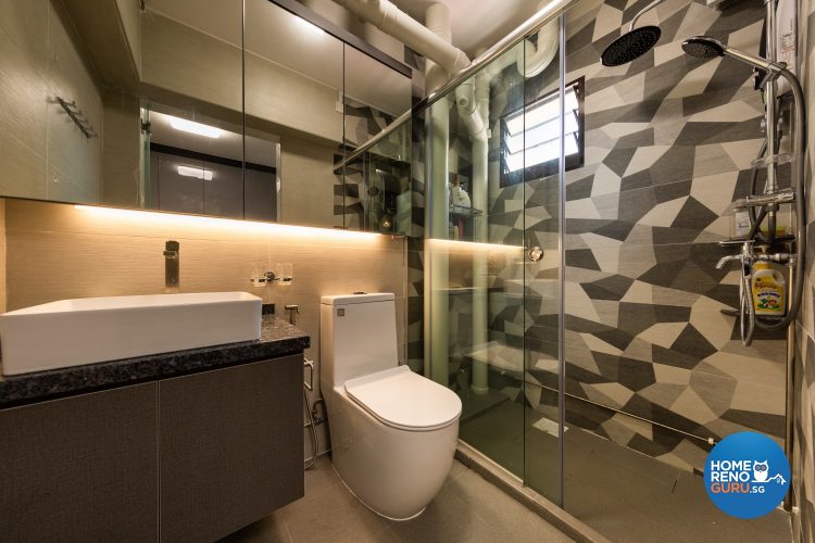 Geometric feature wall, white toilet bowl and glass partitions