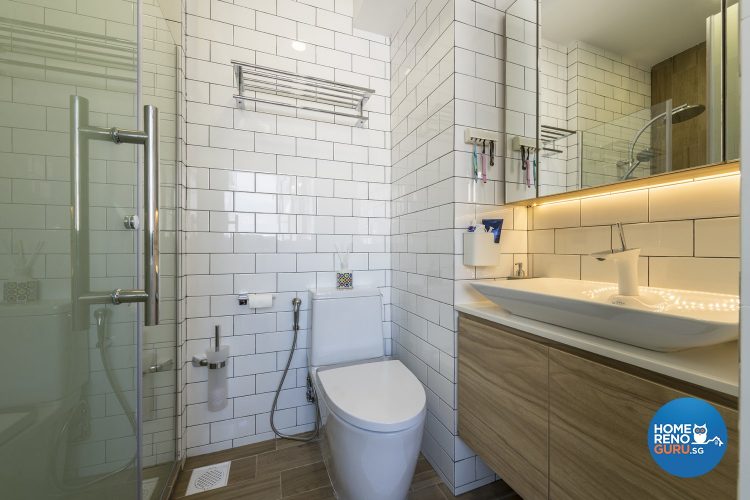 White tiled walls, white toilet bowl, white sink and brown shelves