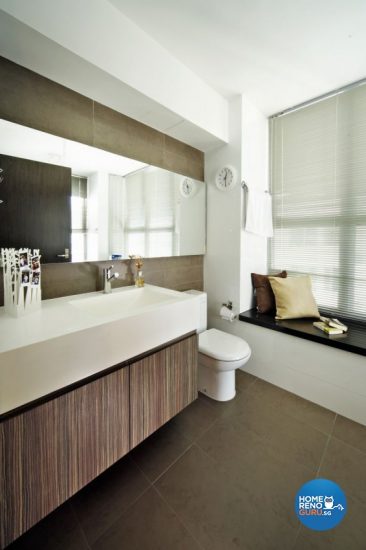 A toilet installed with large windows and blinders, bathed in natural light