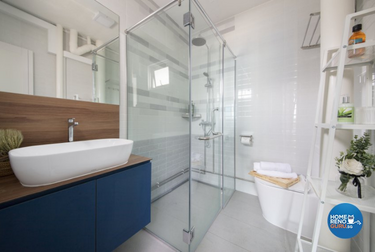 Bathroom with a blue cabinet under the sink and glass shower screens